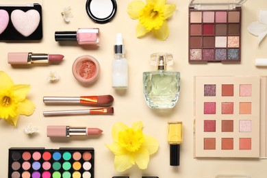 Photo of Flat lay composition with different makeup products and beautiful spring flowers on beige background