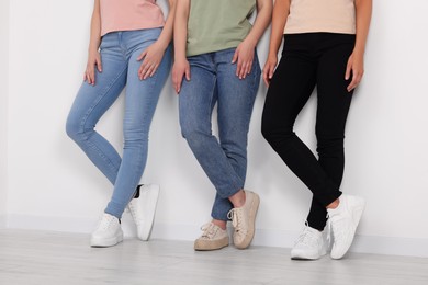 Photo of Women in stylish jeans near white wall, closeup