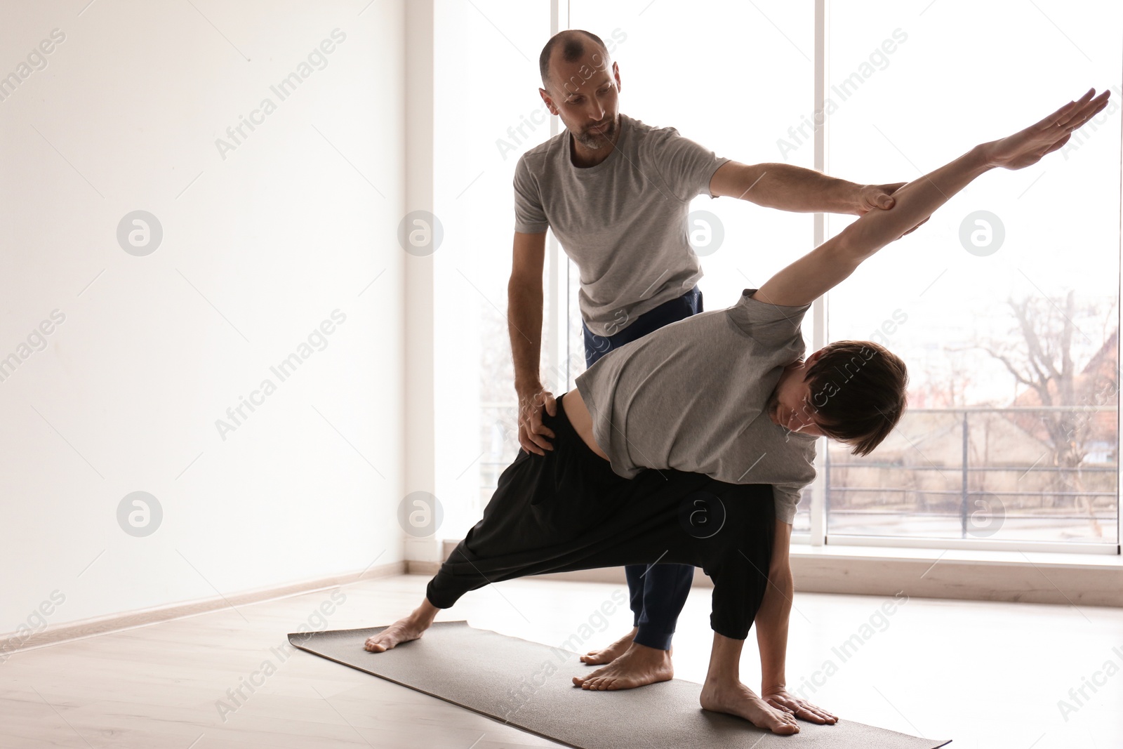 Photo of Young man practicing yoga with instructor indoors