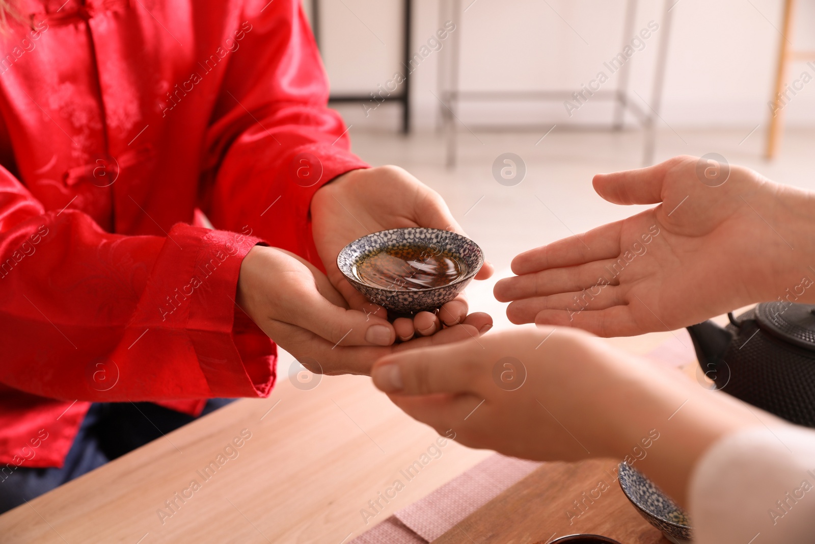 Photo of Master giving freshly brewed tea to guest during ceremony at table, closeup