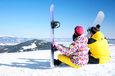 Couple with snowboards on hill, space for text. Winter vacation