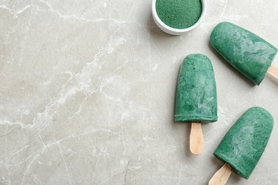 Photo of Flat lay composition with delicious spirulina popsicles and powder on grey background. Space for text