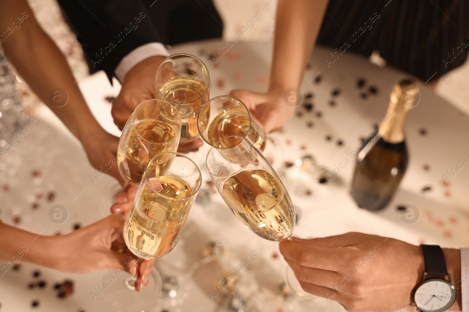Photo of Friends clinking glasses of sparkling wine indoors, closeup. New Year celebration