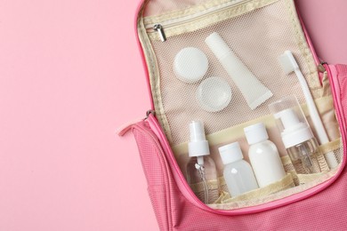 Photo of Compact toiletry bag with cosmetic travel kit on pink background, top view and space for text. Bath accessories
