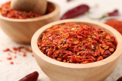 Photo of Chili pepper flakes and pods on light textured table, closeup. Space for text