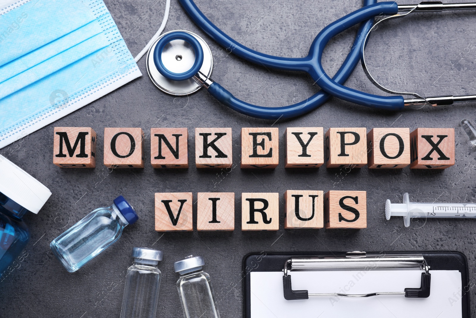 Photo of Flat lay composition with words Monkeypox Virus made of wooden cubes and medical supplies on grey table