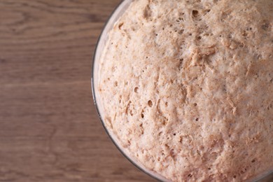 Fresh sourdough in bowl on wooden table, top view. Space for text