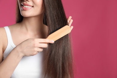 Woman with hair brush on color background, closeup. Space for text