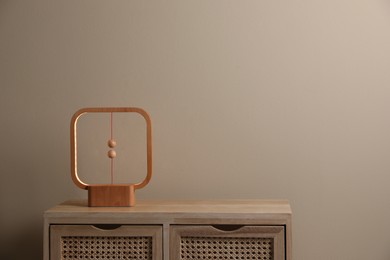 Photo of Wooden cabinet with modern lamp near beige wall in room, space for text