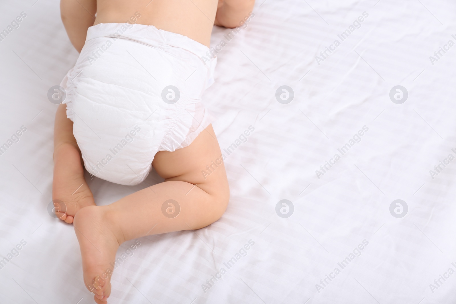 Photo of Back view of cute baby in dry soft diaper on white bed, closeup. Space for text