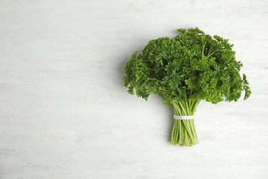 Photo of Bunch of fresh green parsley on white wooden table, top view. Space for text