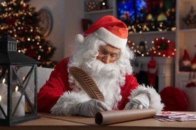 Santa Claus writing letter at table in room decorated for Christmas