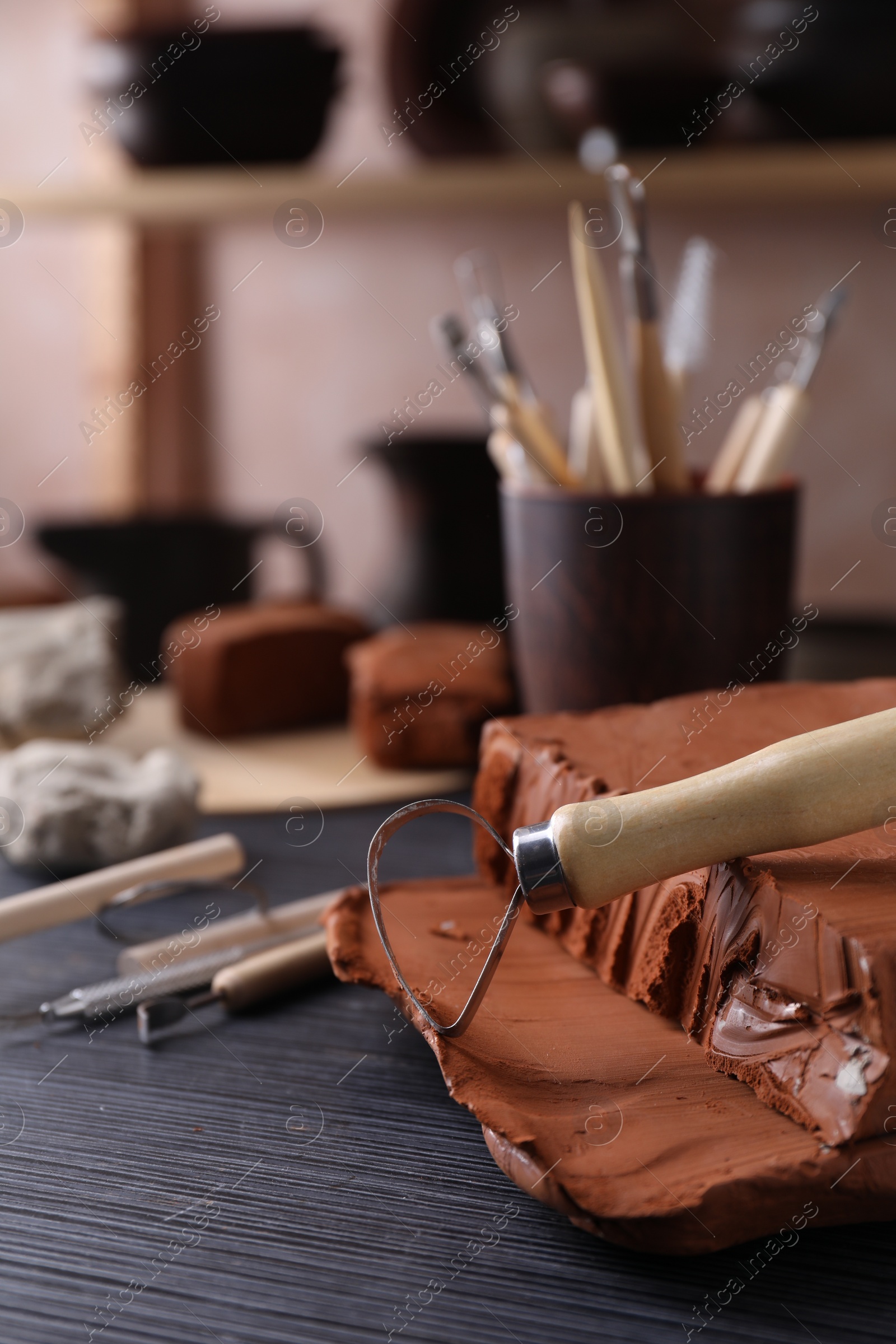 Photo of Clay and loop tool on dark gray wooden table in workshop