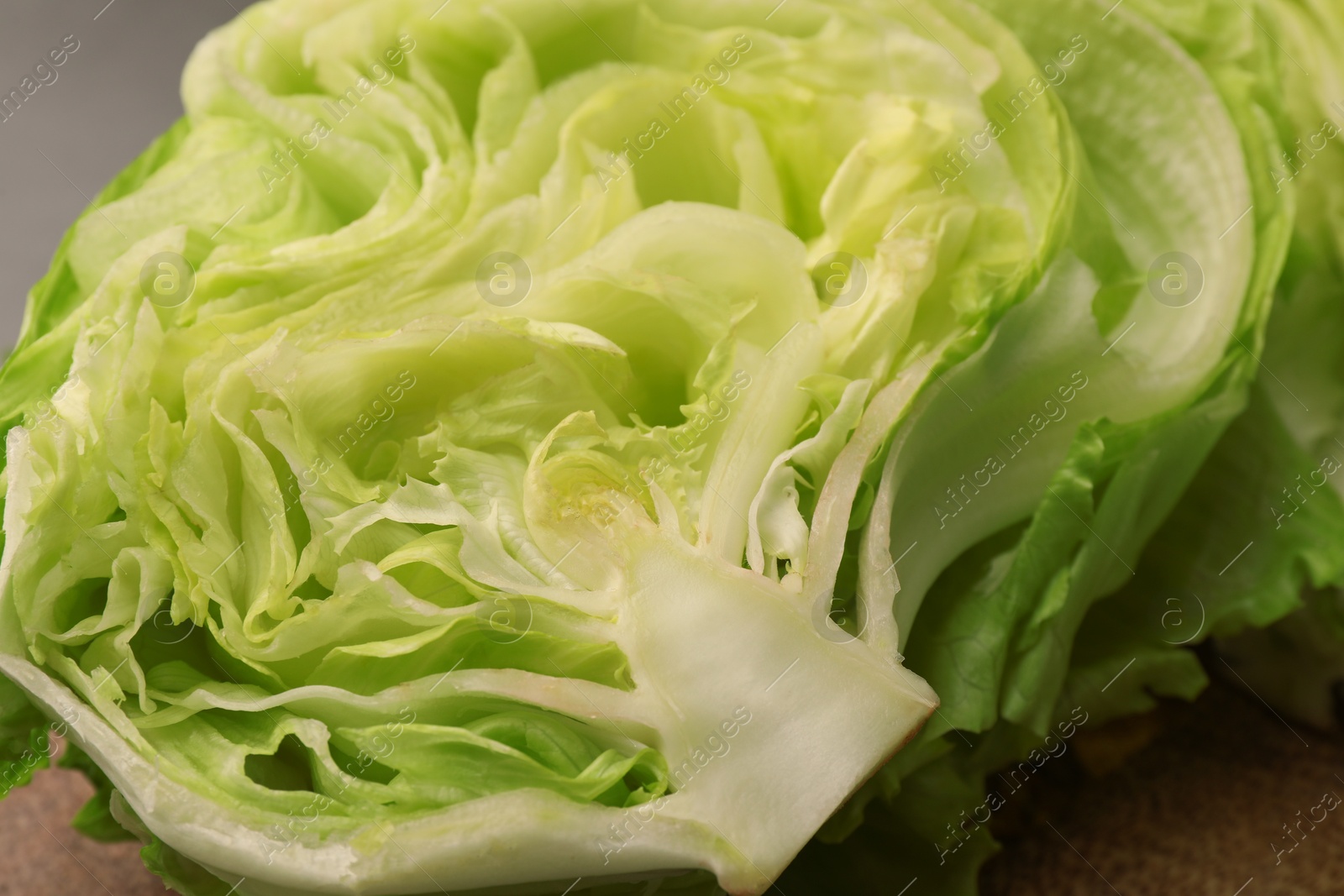 Photo of Half of fresh green iceberg lettuce head on table, closeup