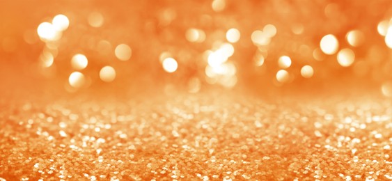 Image of Shiny orange glitter and blurred lights on background, banner design. Bokeh effect