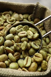 Photo of Green coffee beans and scoop in bag, closeup