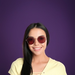 Beautiful woman wearing sunglasses on purple background