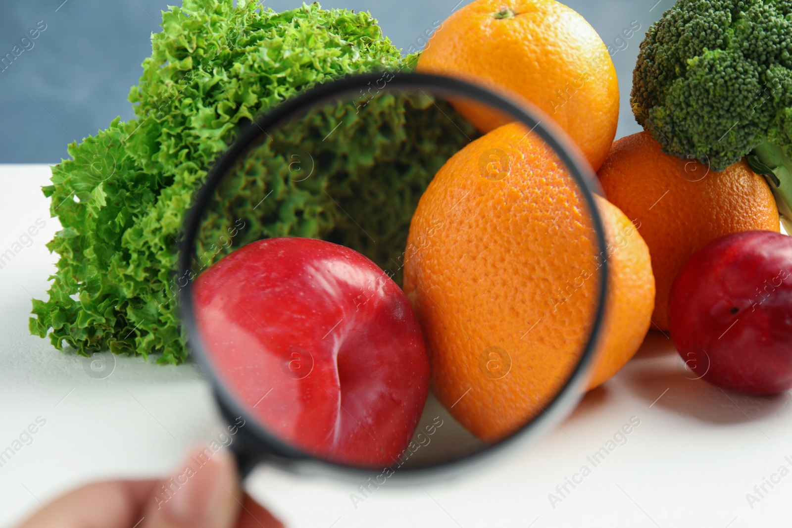 Photo of Woman with magnifying glass exploring vegetables and fruits, closeup. Poison detection