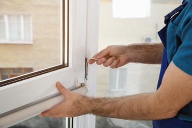 Construction worker installing plastic window in house, closeup