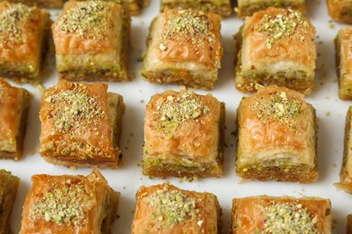 Photo of Delicious fresh baklava with chopped nuts on white table, above view. Eastern sweets
