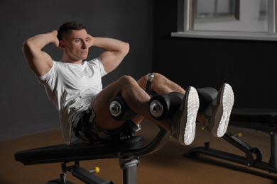 Man working out on adjustable sit up bench in modern gym