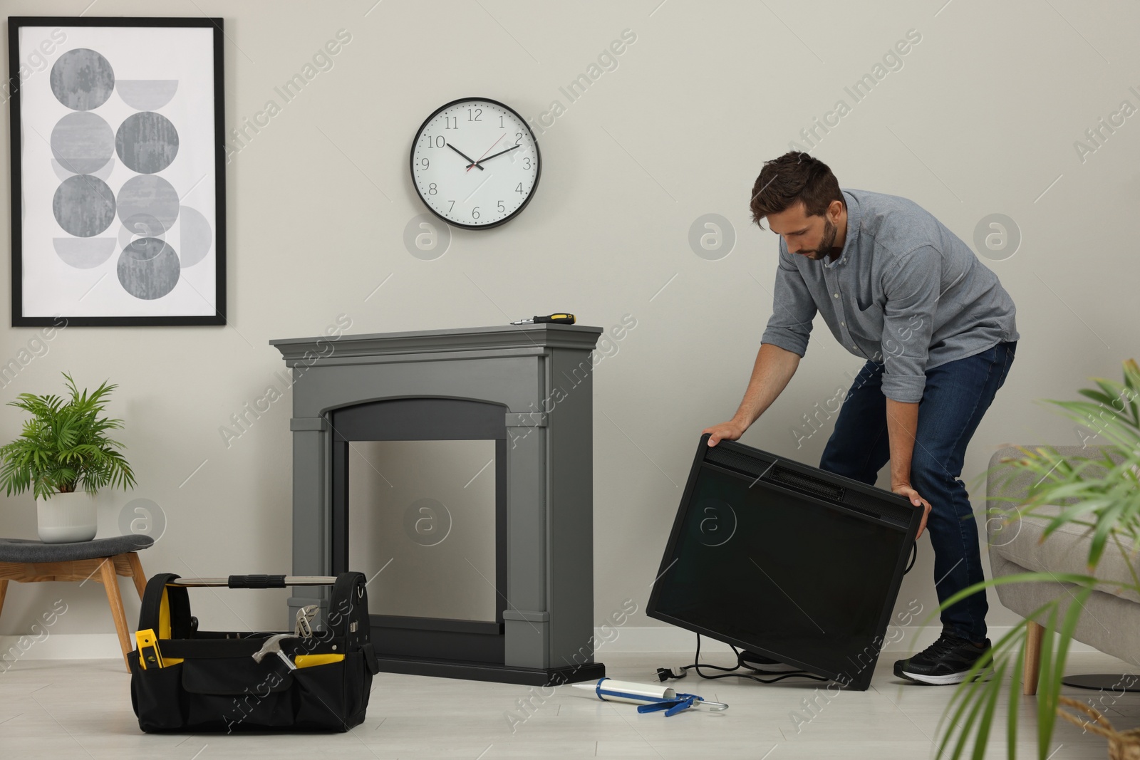 Photo of Man installing electric fireplace near wall in room