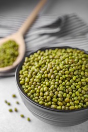 Photo of Bowl with green mung beans on light grey table, closeup