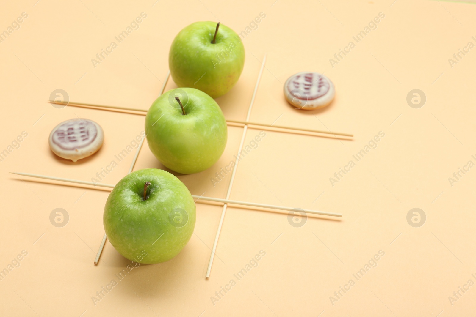 Photo of Tic tac toe game made with apples and cookies on beige background