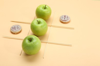 Photo of Tic tac toe game made with apples and cookies on beige background