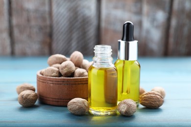 Photo of Bottles of nutmeg oil and nuts on turquoise wooden table