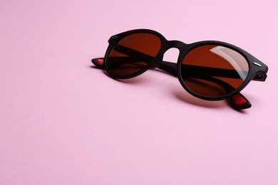 Stylish sunglasses on pink background, space for text. Fashionable accessory