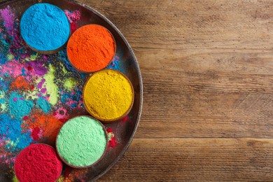 Photo of Colorful powder dyes on wooden background, top view with space for text. Holi festival