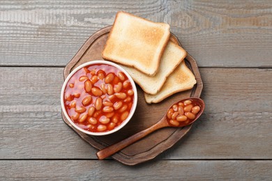 Photo of Toasts and delicious canned beans on wooden table, top view