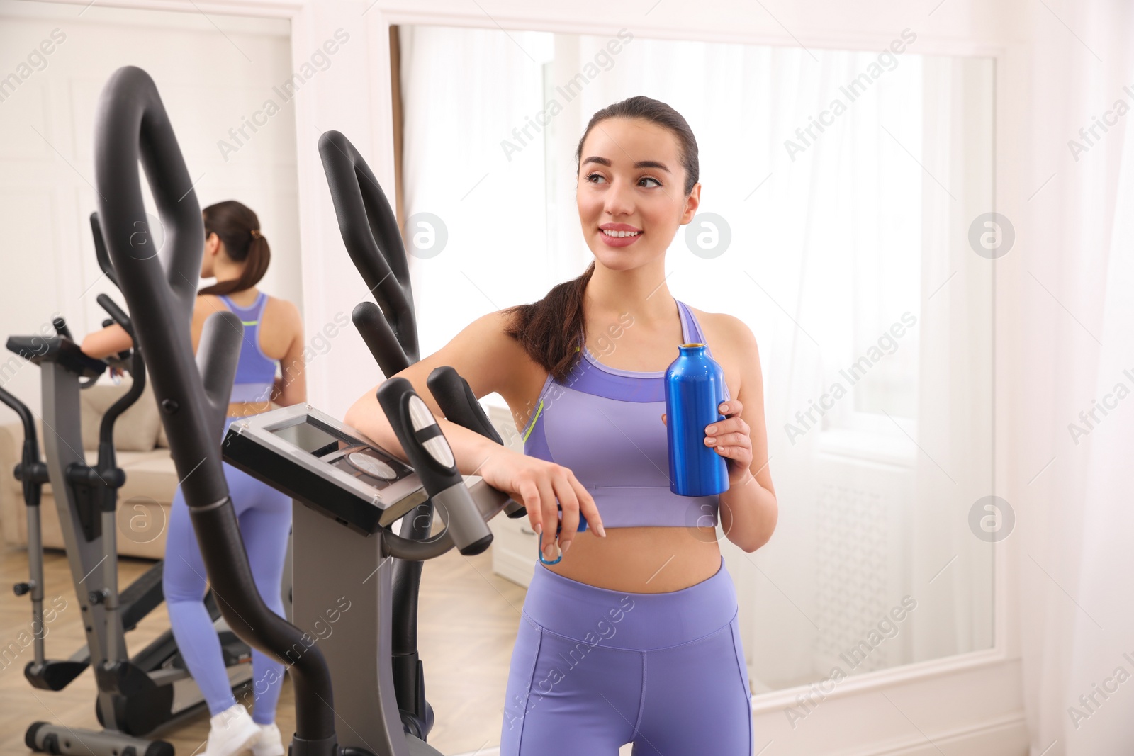 Photo of Woman with bottle near elliptical machine indoors