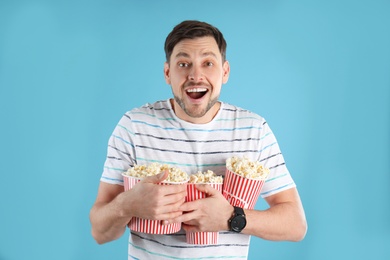 Photo of Emotional man with tasty popcorn on color background