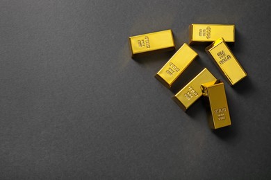 Photo of Many shiny gold bars on black background, flat lay. Space for text