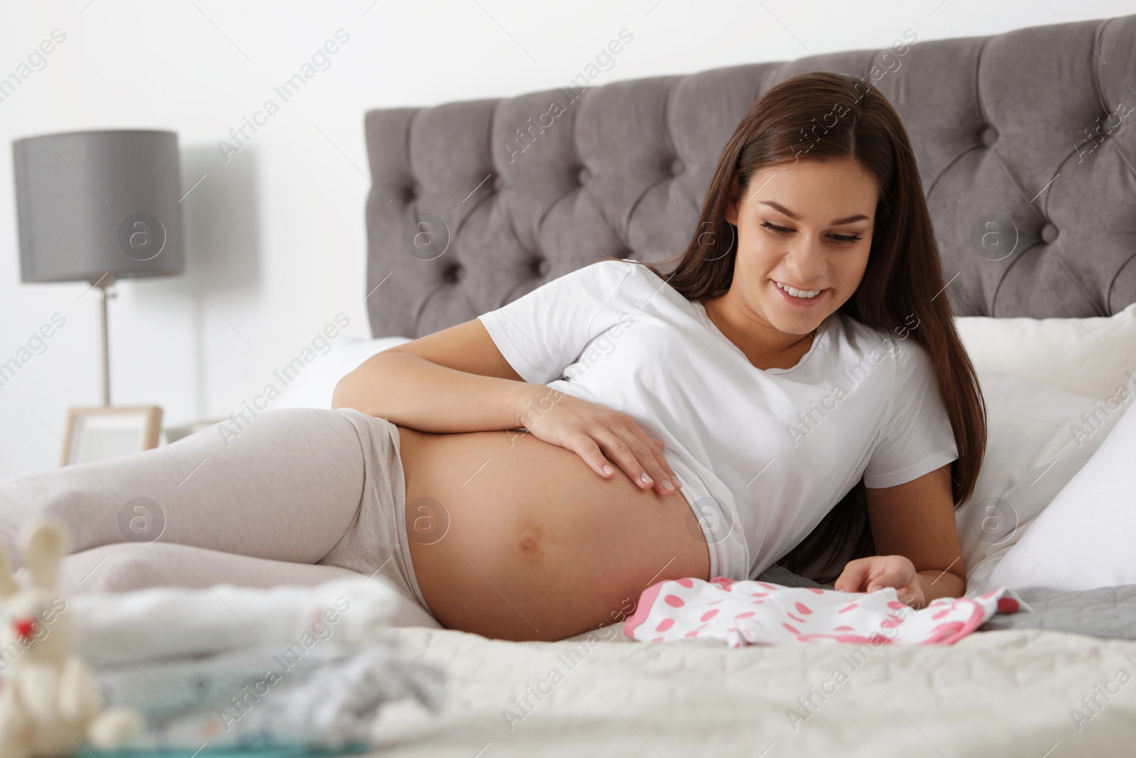 Photo of Pregnant woman preparing baby clothes for maternity hospital at home