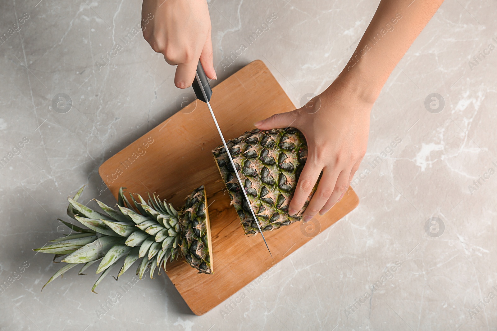 Photo of Woman cutting fresh pineapple on wooden board