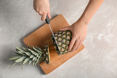 Photo of Woman cutting fresh pineapple on wooden board