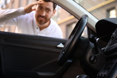 Automobile lockout, key forgotten inside, selective focus. Emotional man looking through car window