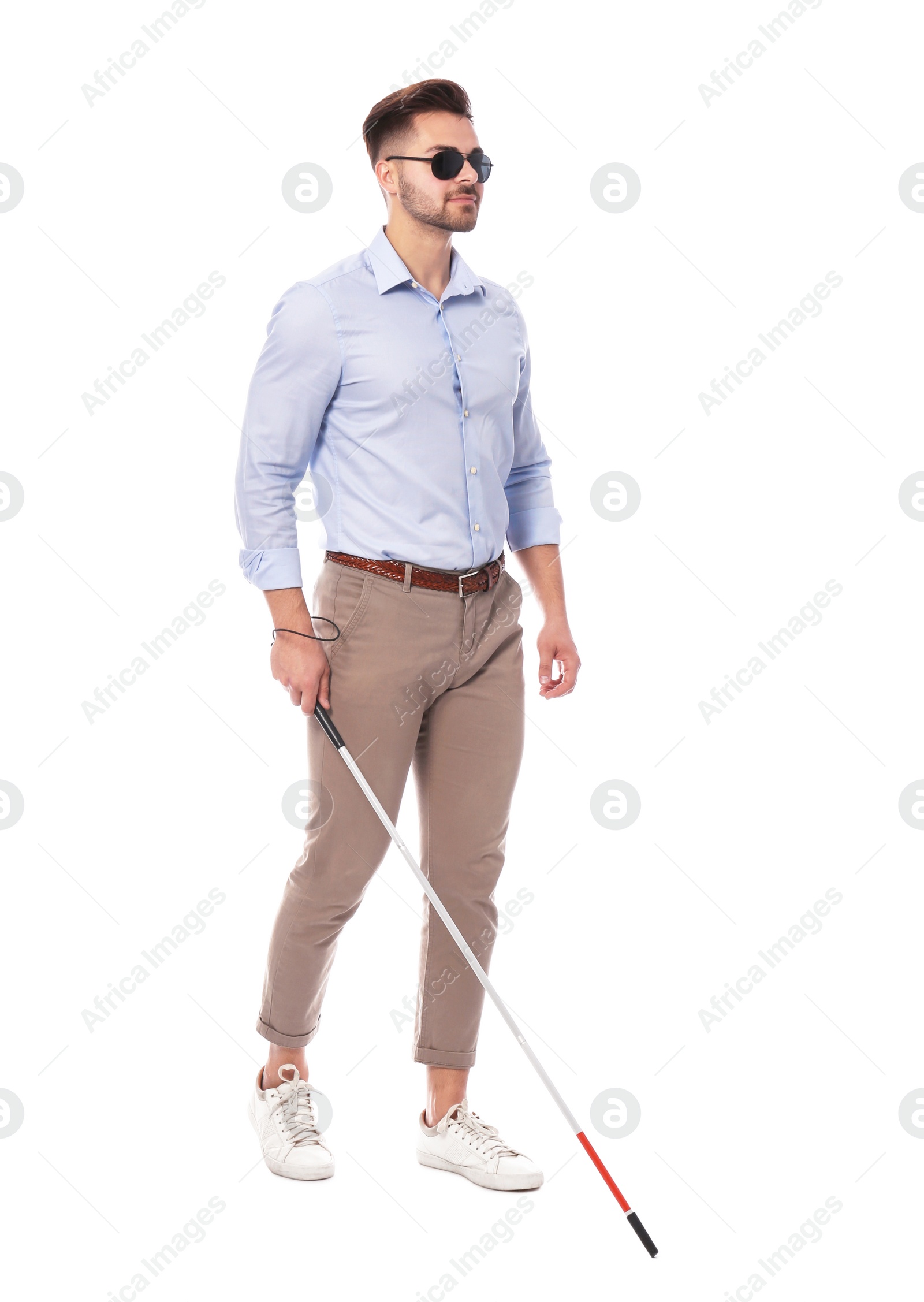 Photo of Young blind person with long cane walking on white background