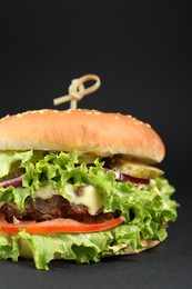 Photo of Delicious burger with beef patty and lettuce on black background