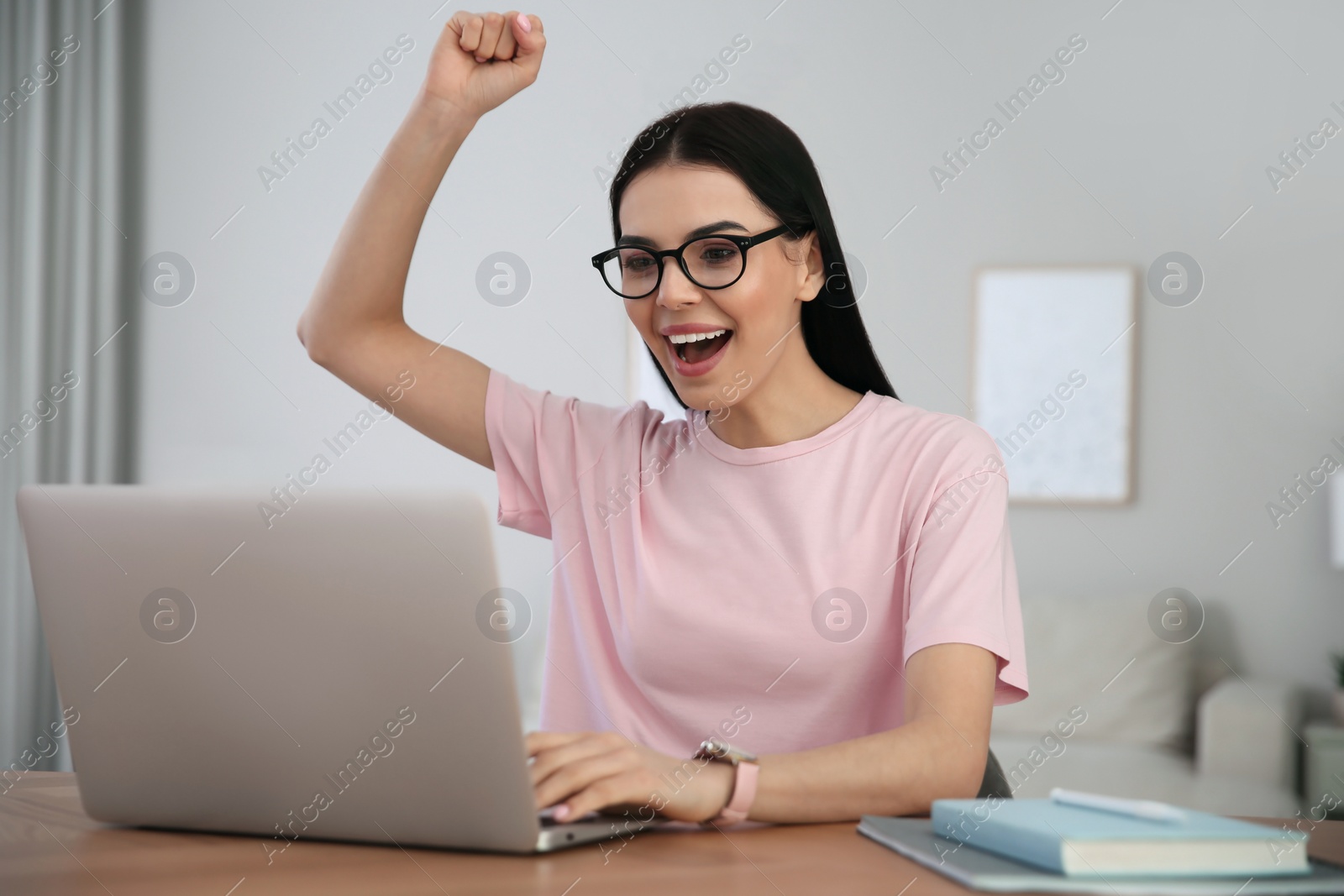 Photo of Emotional woman participating in online auction using laptop at home