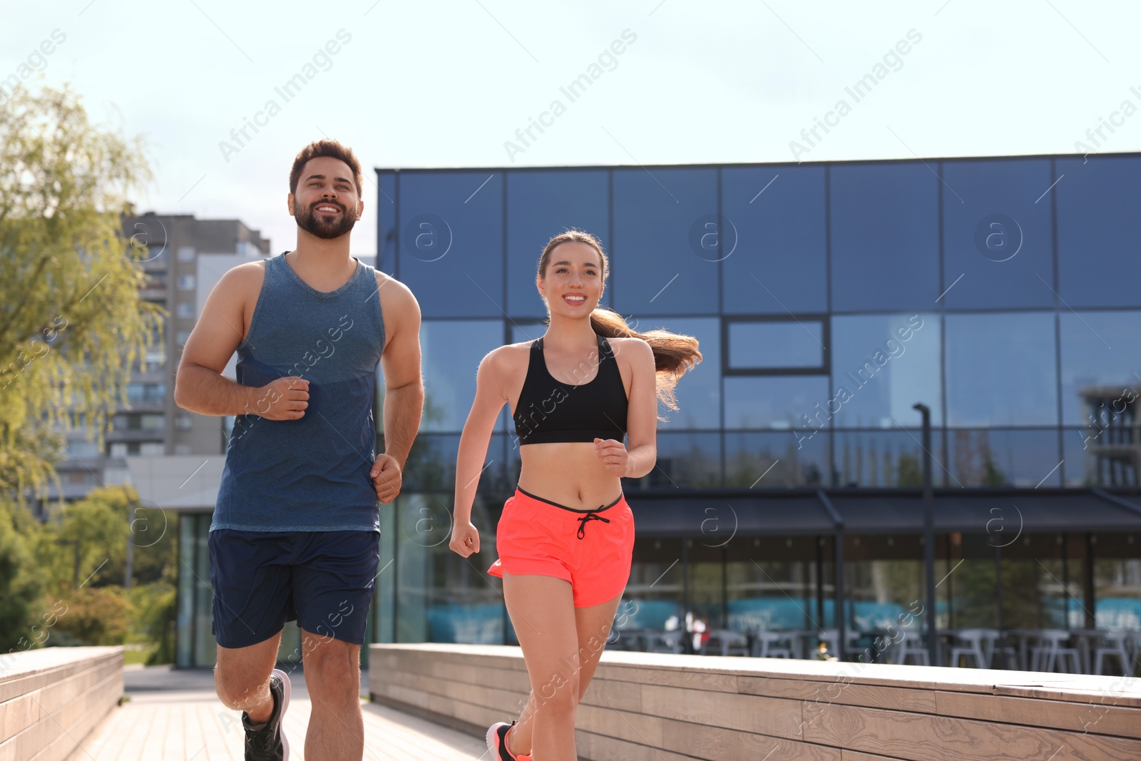 Photo of Healthy lifestyle. Happy couple running outdoors on sunny day, space for text