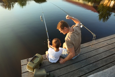 Dad and son fishing together on sunny day