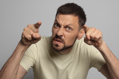 Photo of Aggressive man pointing on grey background. Hate concept