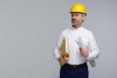 Photo of Architect in hard hat holding folder and draft on grey background. Space for text