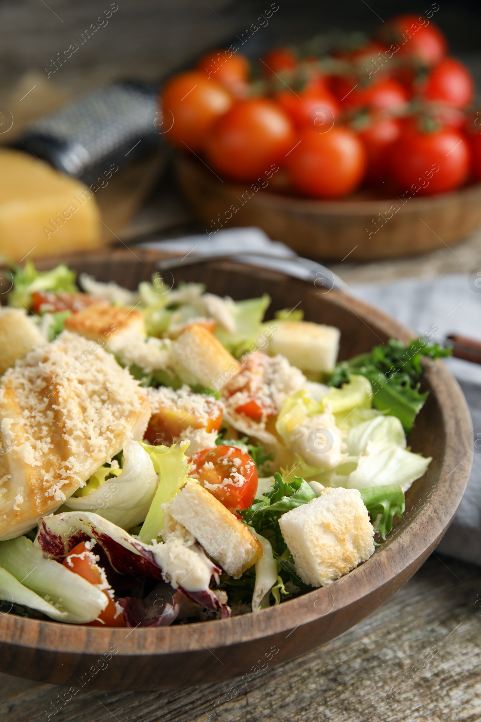 Photo of Delicious Caesar salad in bowl on wooden table, closeup