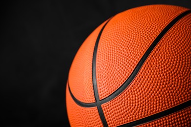 Photo of Closeup view of orange ball on black background, space for text. Basketball equipment