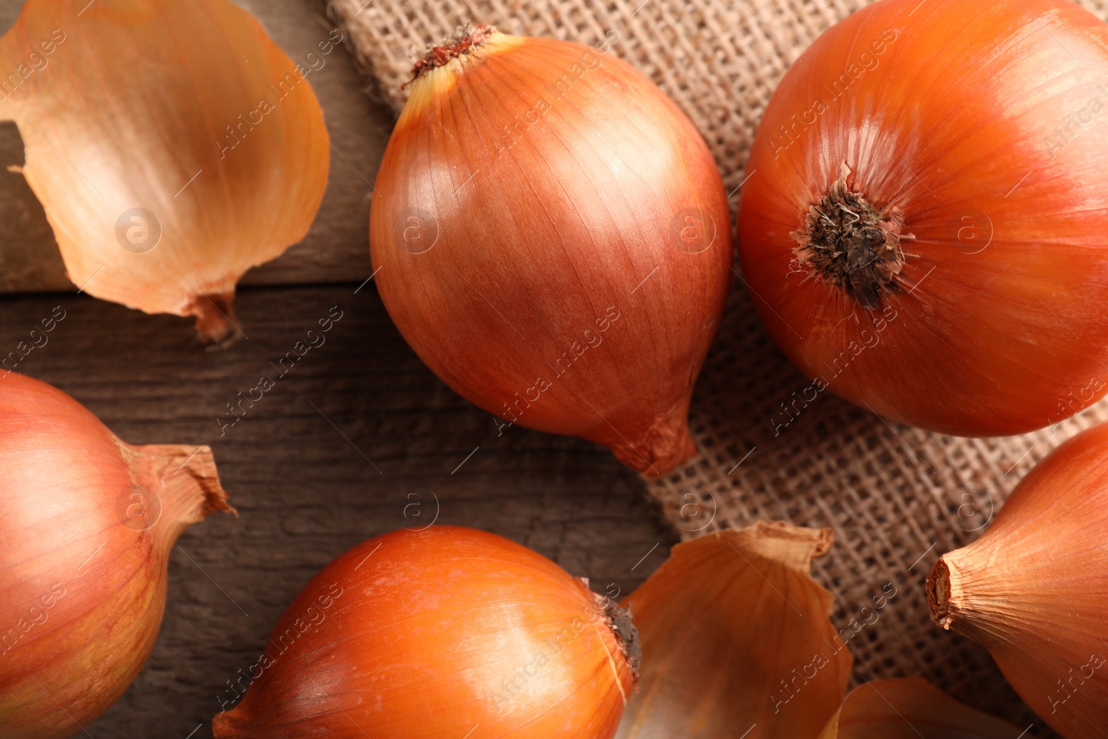 Photo of Many ripe onions on wooden table, flat lay